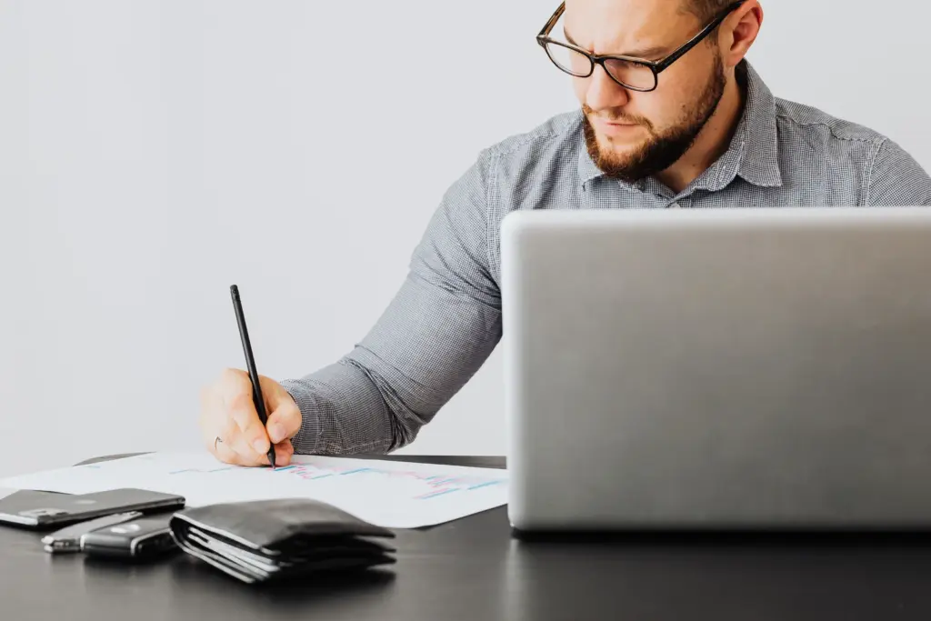 Freiberufler arbeitet mit Laptop und Finanzunterlagen am Schreibtisch