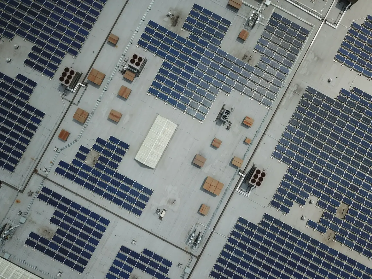 Luftaufnahme zahlreicher Solarmodule auf einem großen Gewerbedach