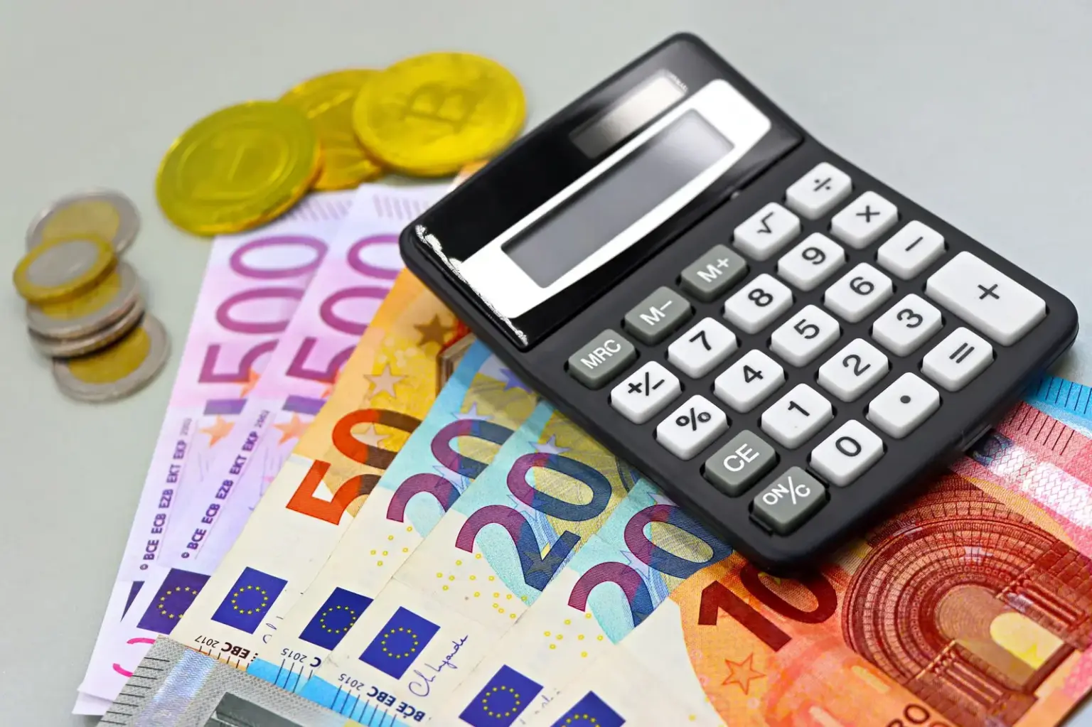 Eurobanknoten und Münzen unter einem Taschenrechner als Symbol für öffentliches Finanzvermögen