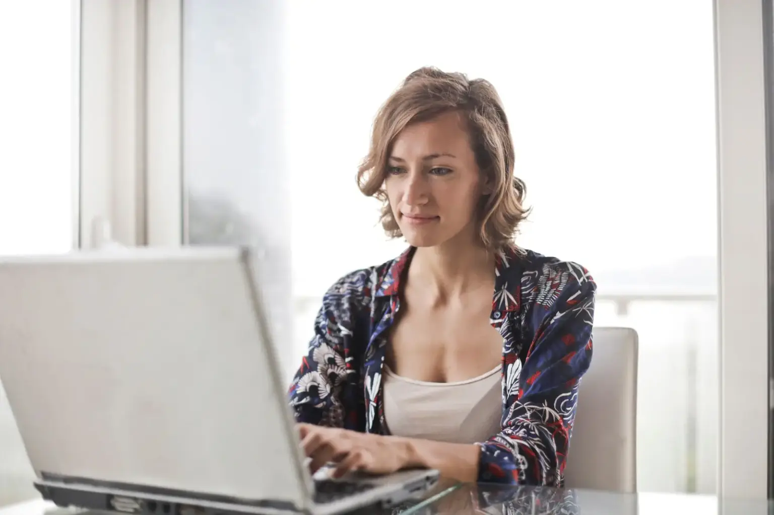 Frau arbeitet an einem Laptop in einem hellen Homeoffice