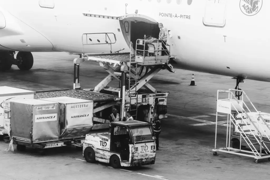 Frachtcontainer werden in ein Flugzeug auf einem Flughafenvorfeld verladen
