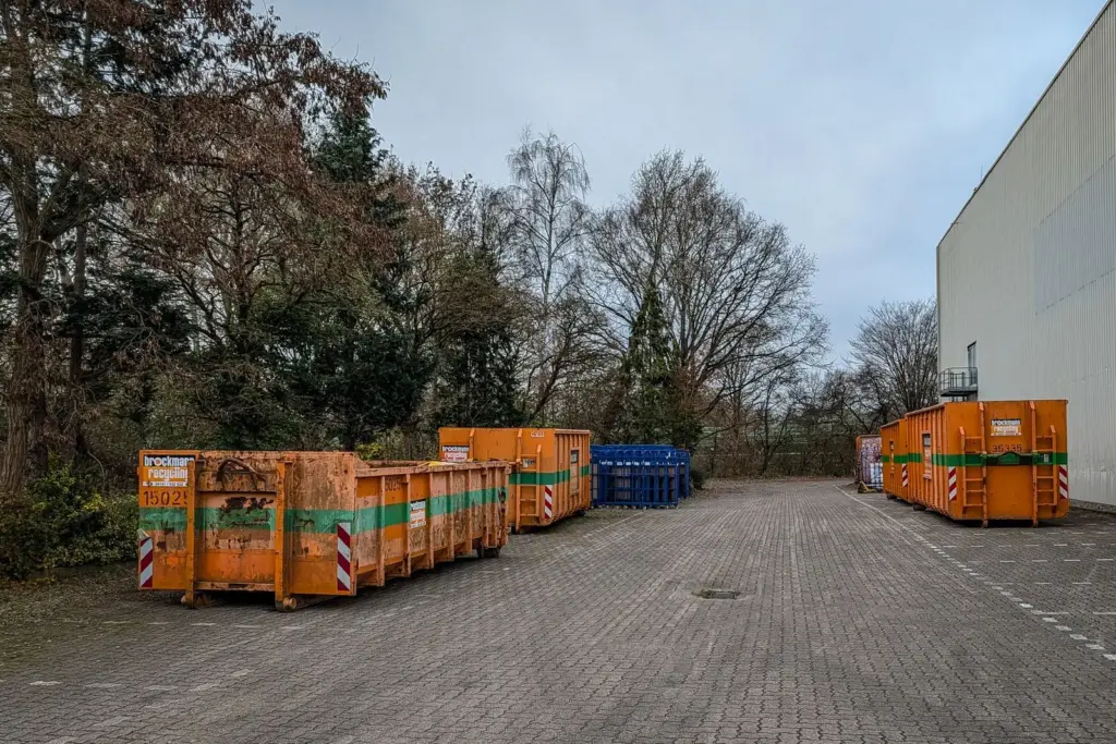 Mehrere Recycling- und Abfallcontainer auf dem Gelände eines Gewerbebetriebs