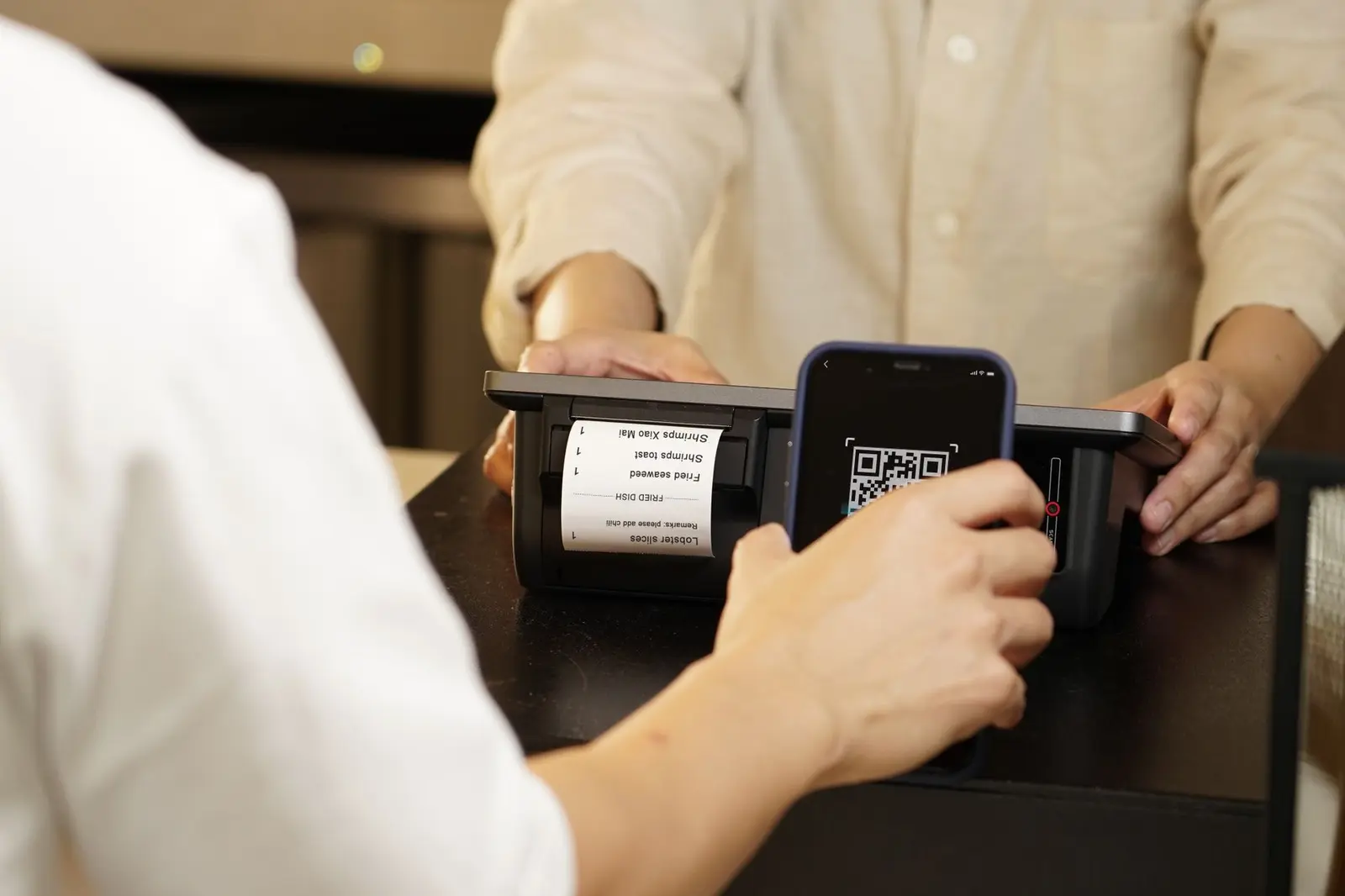 Smartphone scannt einen QR-Code an einem digitalen Kassensystem