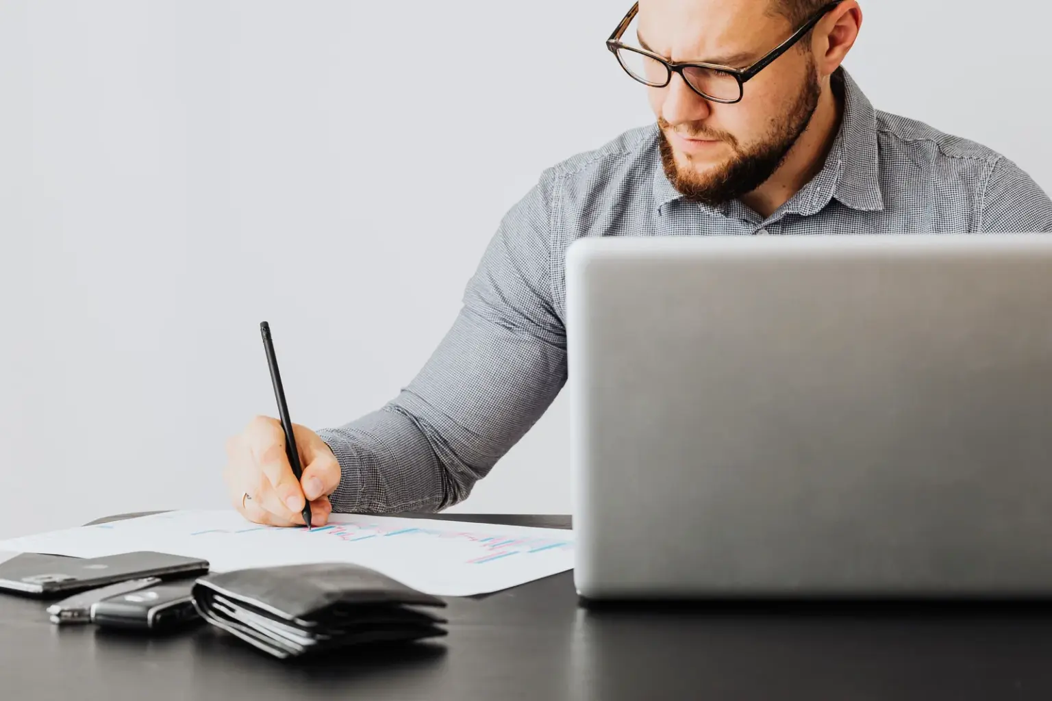 Freiberufler arbeitet mit Laptop und Finanzunterlagen am Schreibtisch