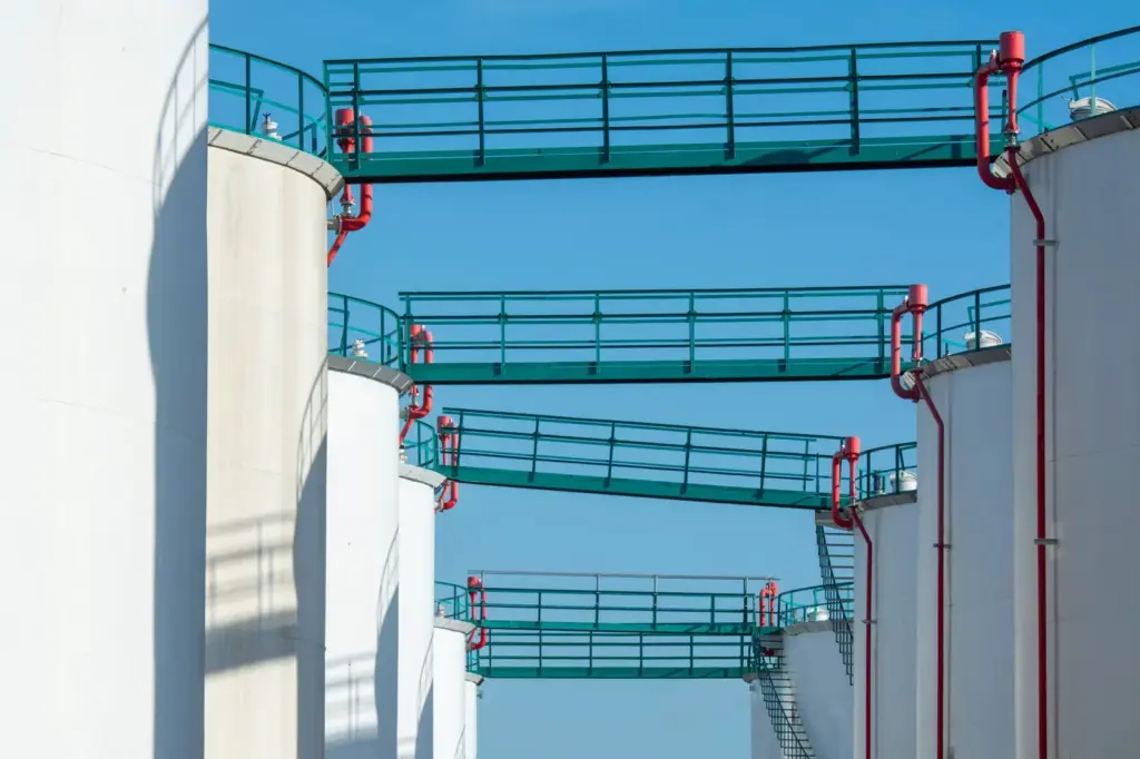 Weiße industrielle Lagertanks für Mineralölerzeugnisse unter blauem Himmel