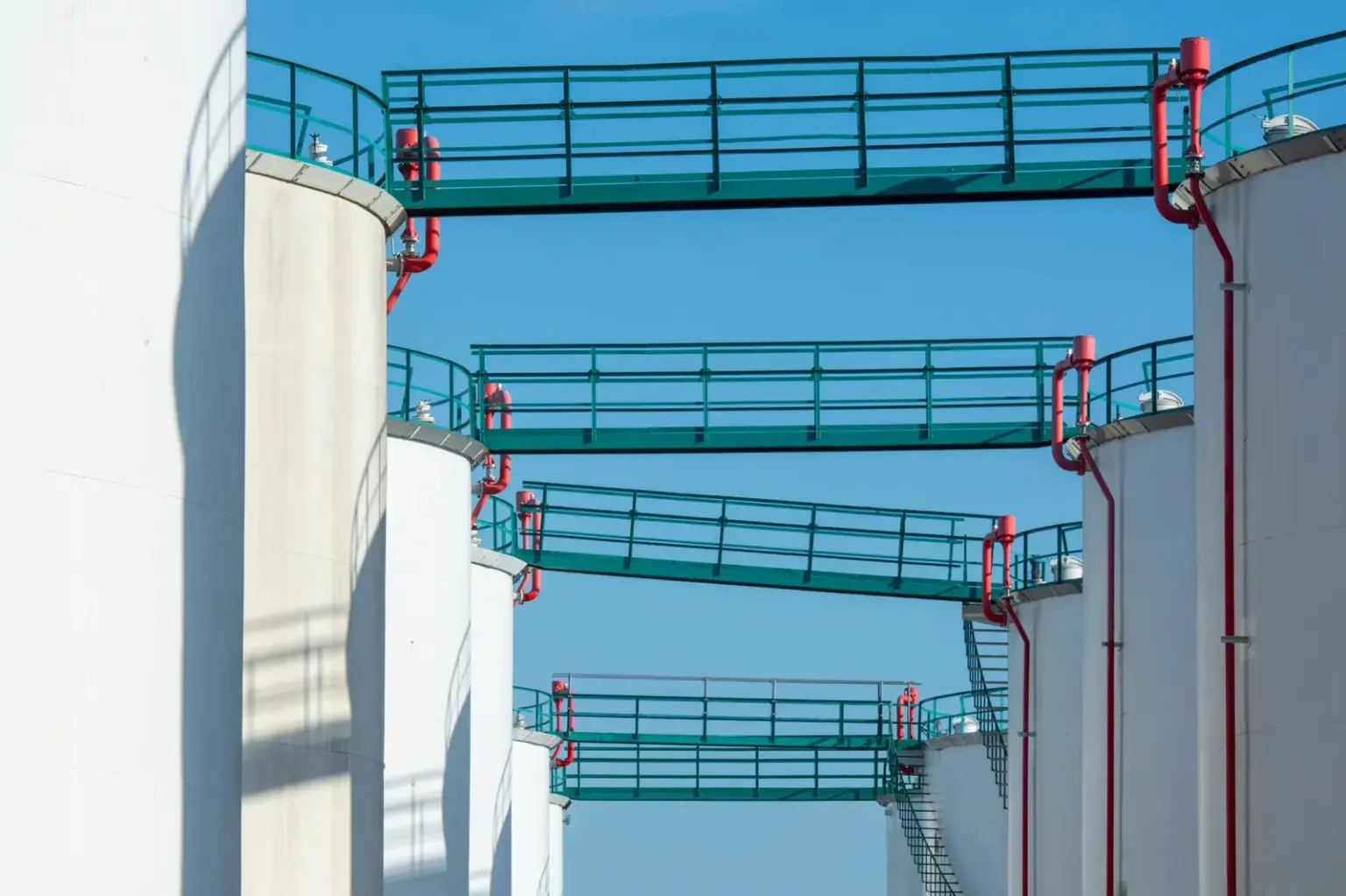 Weiße industrielle Lagertanks für Mineralölerzeugnisse unter blauem Himmel