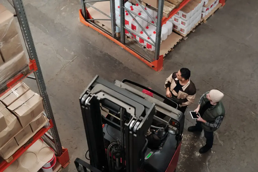 Zwei Logistikmitarbeiter besprechen Abläufe neben einem Gabelstapler