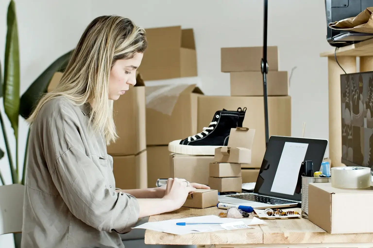 Inhaberin eines Onlineshops verpackt Bestellungen am Arbeitsplatz