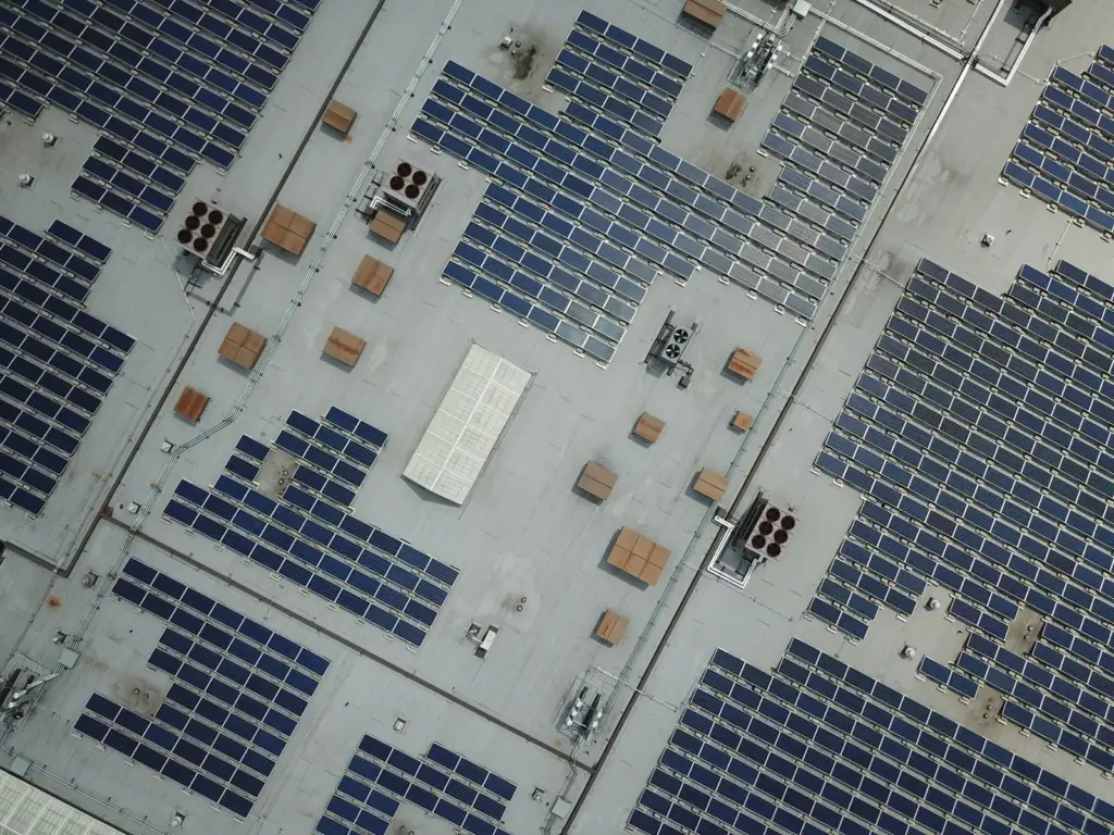 Luftaufnahme zahlreicher Solarmodule auf einem großen Gewerbedach