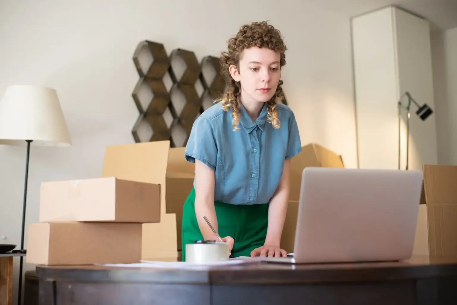 Onlinehändlerin arbeitet am Laptop zwischen Versandkartons