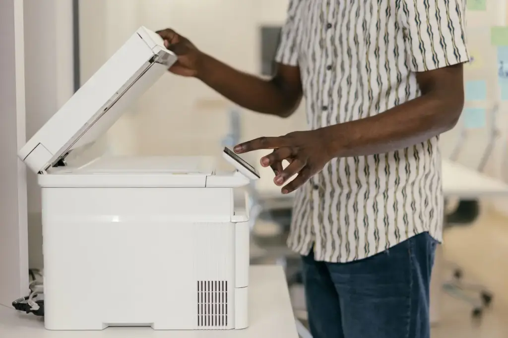 Mitarbeiter bedient einen weißen Multifunktionsdrucker in einem Büro