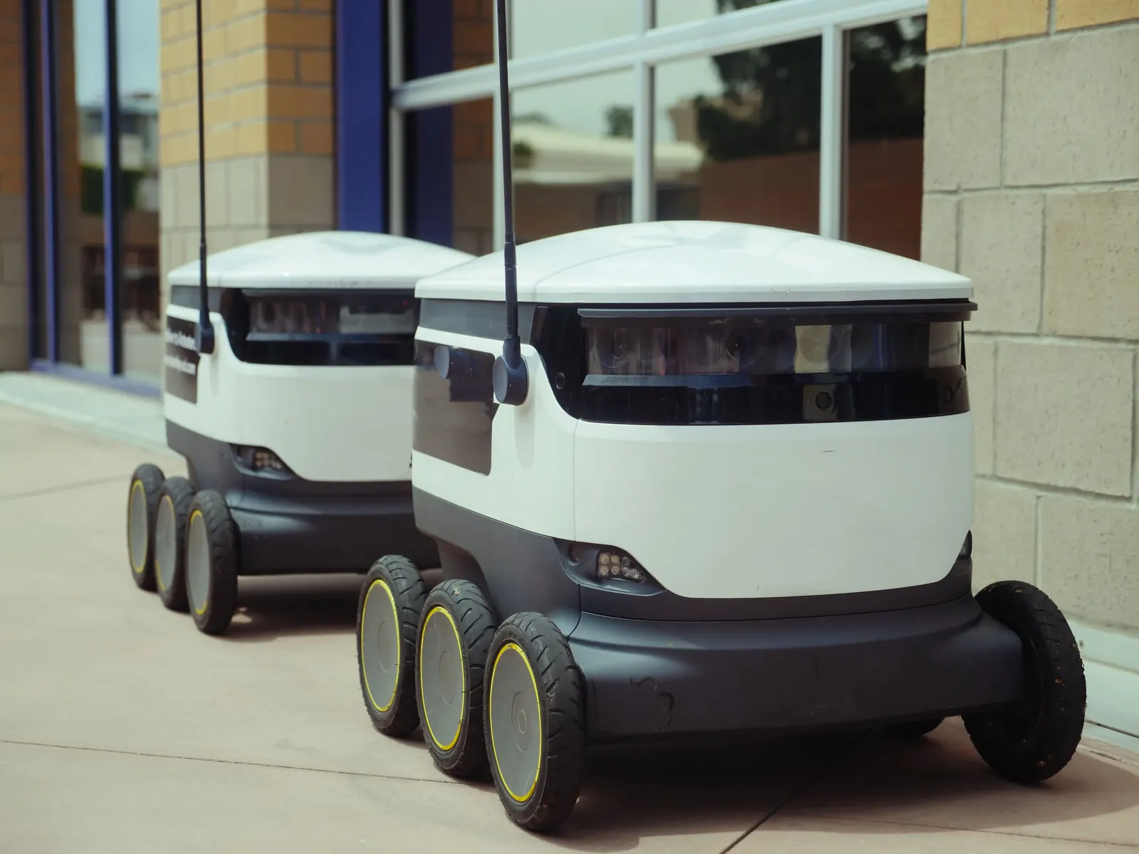 Zwei autonome Lieferroboter vor einem Gebäude im praktischen Außeneinsatz