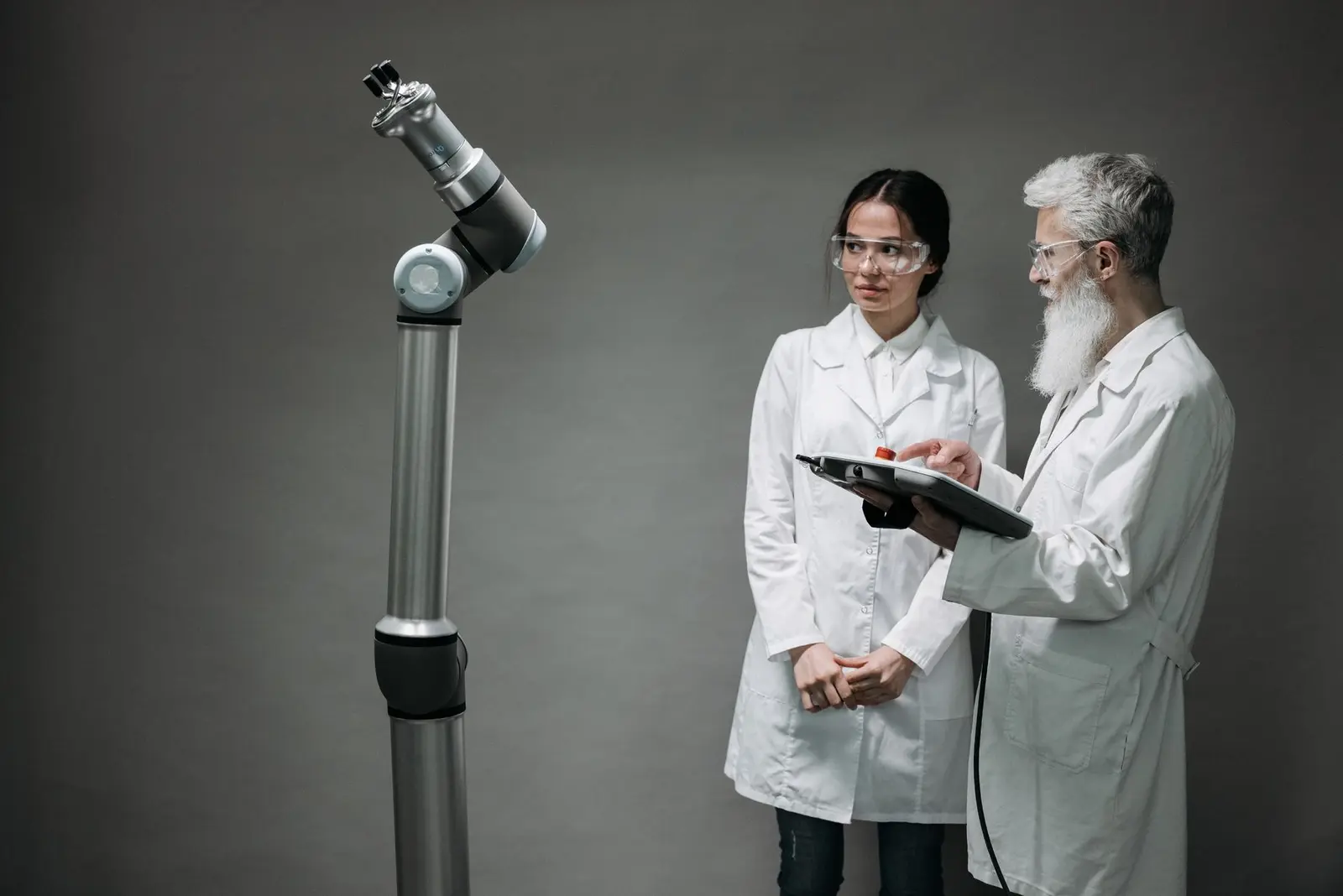 Zwei Forschende untersuchen gemeinsam einen Roboterarm im Labor