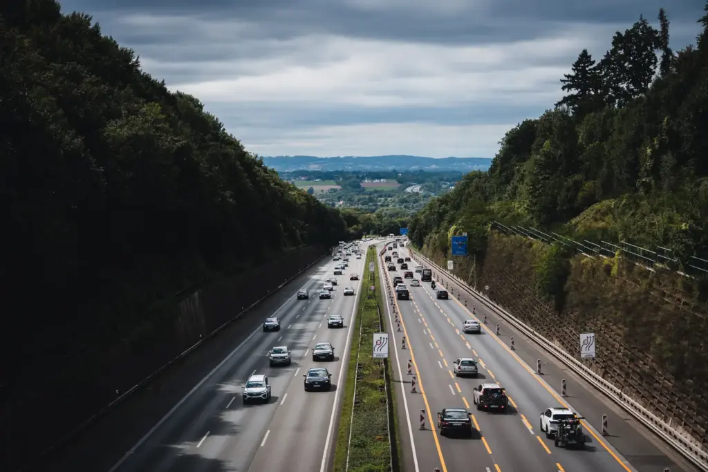 Autos und Lastwagen fahren auf einer Autobahn durch eine bewaldete Landschaft in Deutschland