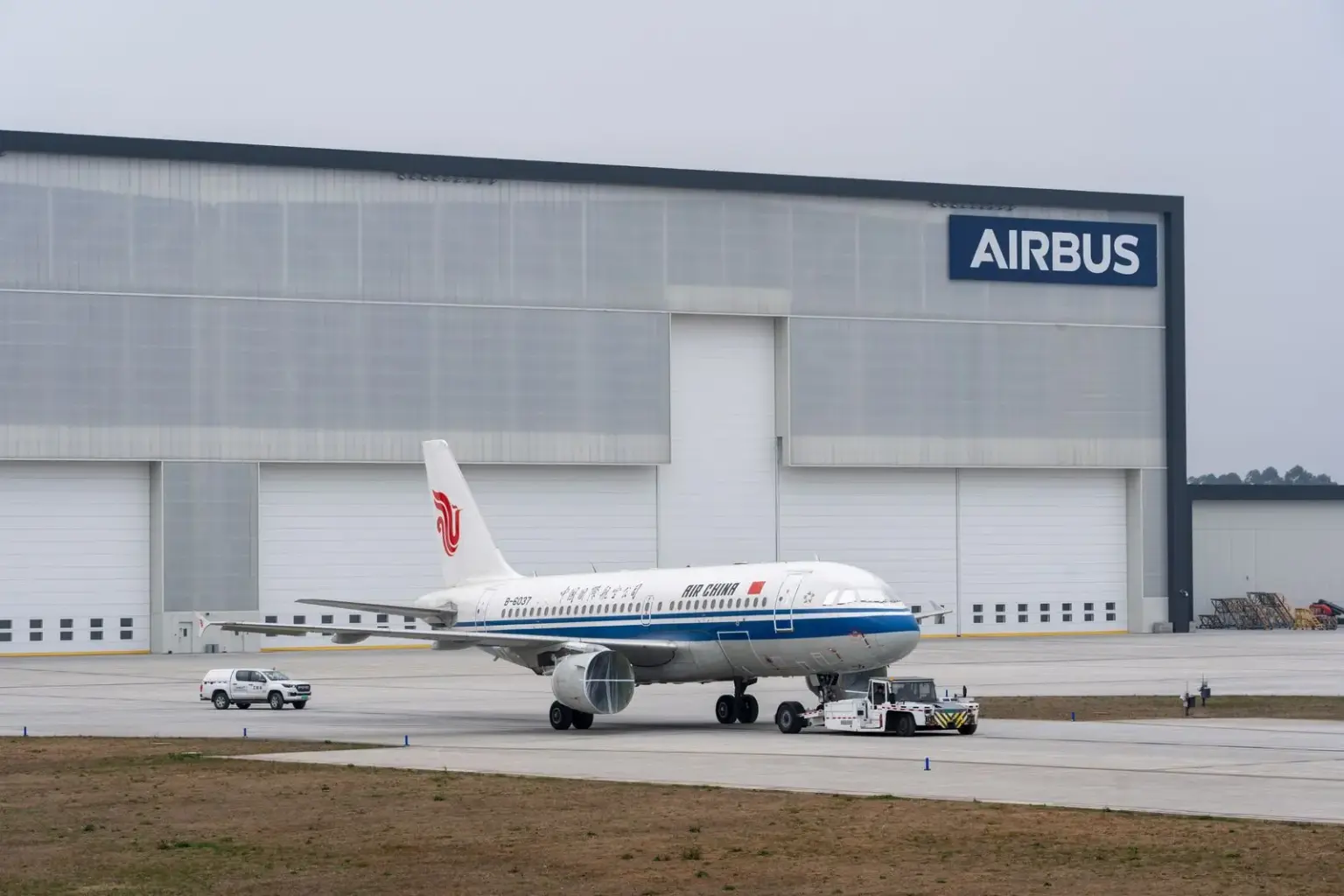 Passagierflugzeug vor einer großen Werkhalle mit Airbus-Schriftzug