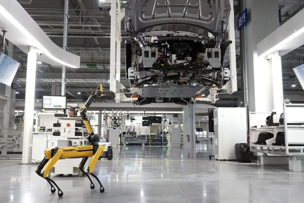 Weiße Fahrzeugkarosserie in einer automatisierten Fabrikhalle neben einem mobilen Roboter
