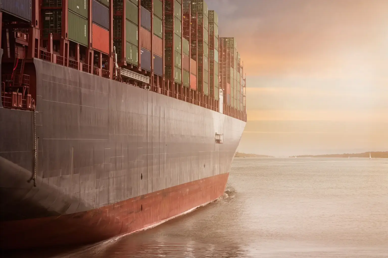 Großes Containerschiff auf ruhigem Wasser bei Sonnenuntergang als Symbol für internationalen Warenhandel
