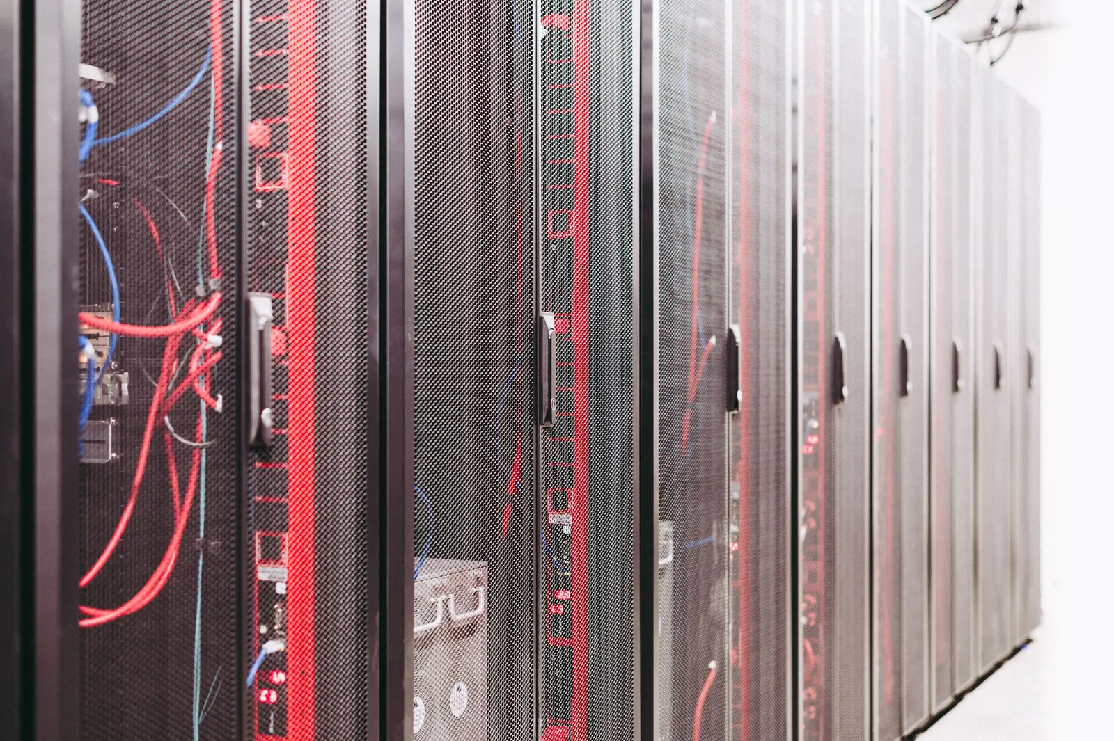 Reihe schwarzer Serverracks mit rot beleuchteten Kabeln in einem Rechenzentrum