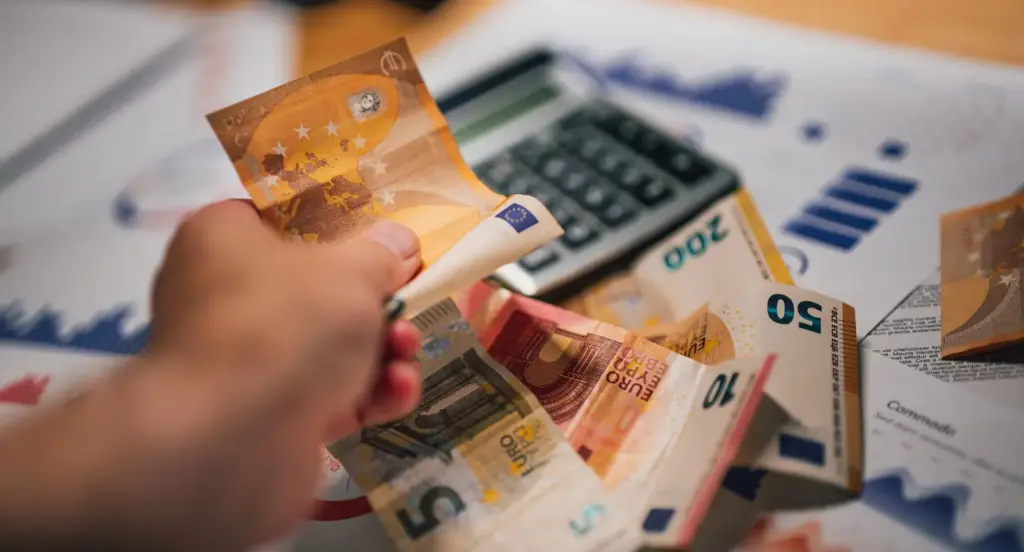 Eurobanknoten liegen mit Finanzunterlagen und Taschenrechner auf einem Tisch