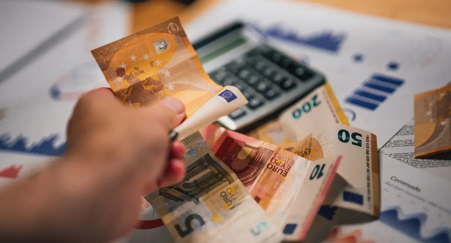 Eurobanknoten liegen mit Finanzunterlagen und Taschenrechner auf einem Tisch
