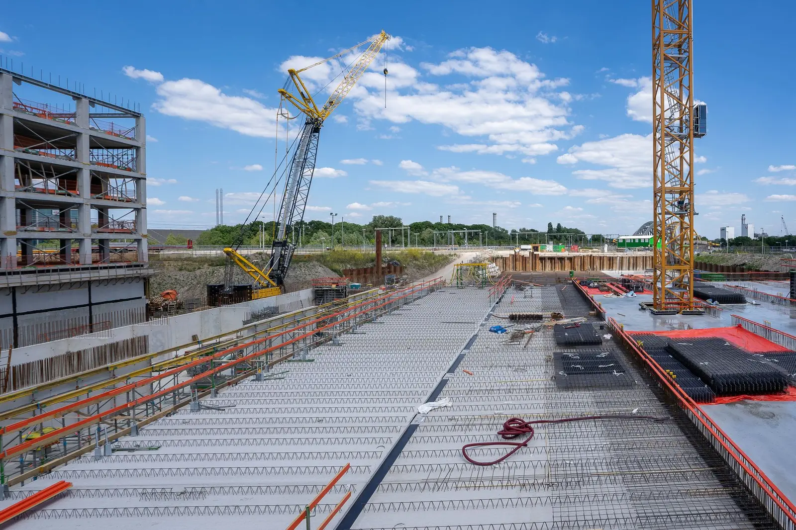 Betonrohbau, Baugrube und Kräne auf einer großen Hochbaustelle