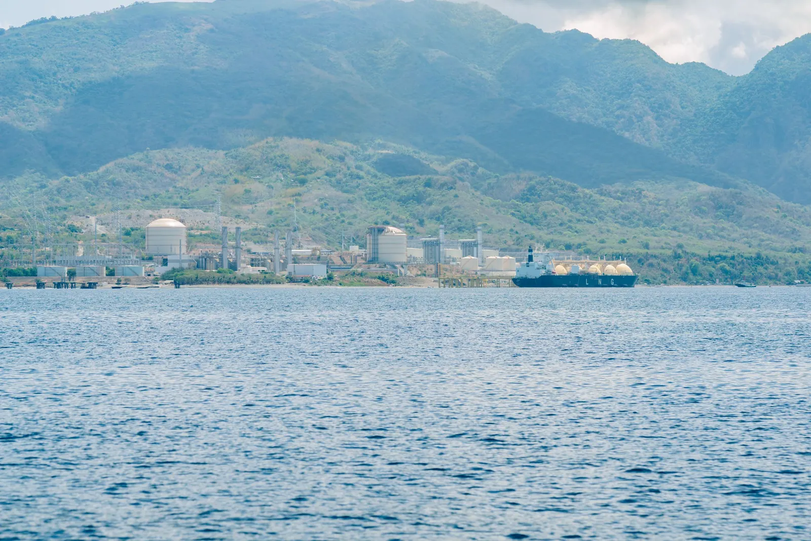 LNG-Terminal an einer Küste mit Tanker und Berglandschaft