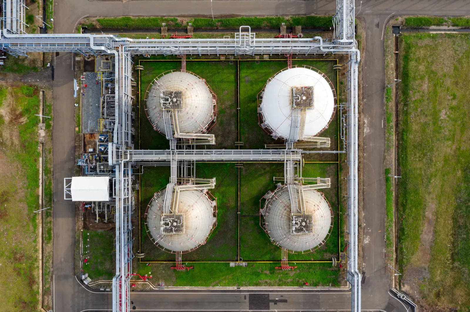 Vier industrielle Lagertanks mit Rohrleitungen aus der Vogelperspektive