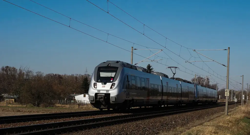 Moderner elektrischer Regionalzug unter Oberleitungen auf einer ländlichen Bahnstrecke
