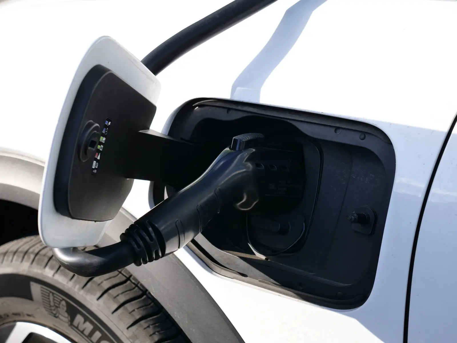 Ladekabel steckt im geöffneten Ladeanschluss eines weißen Elektroautos