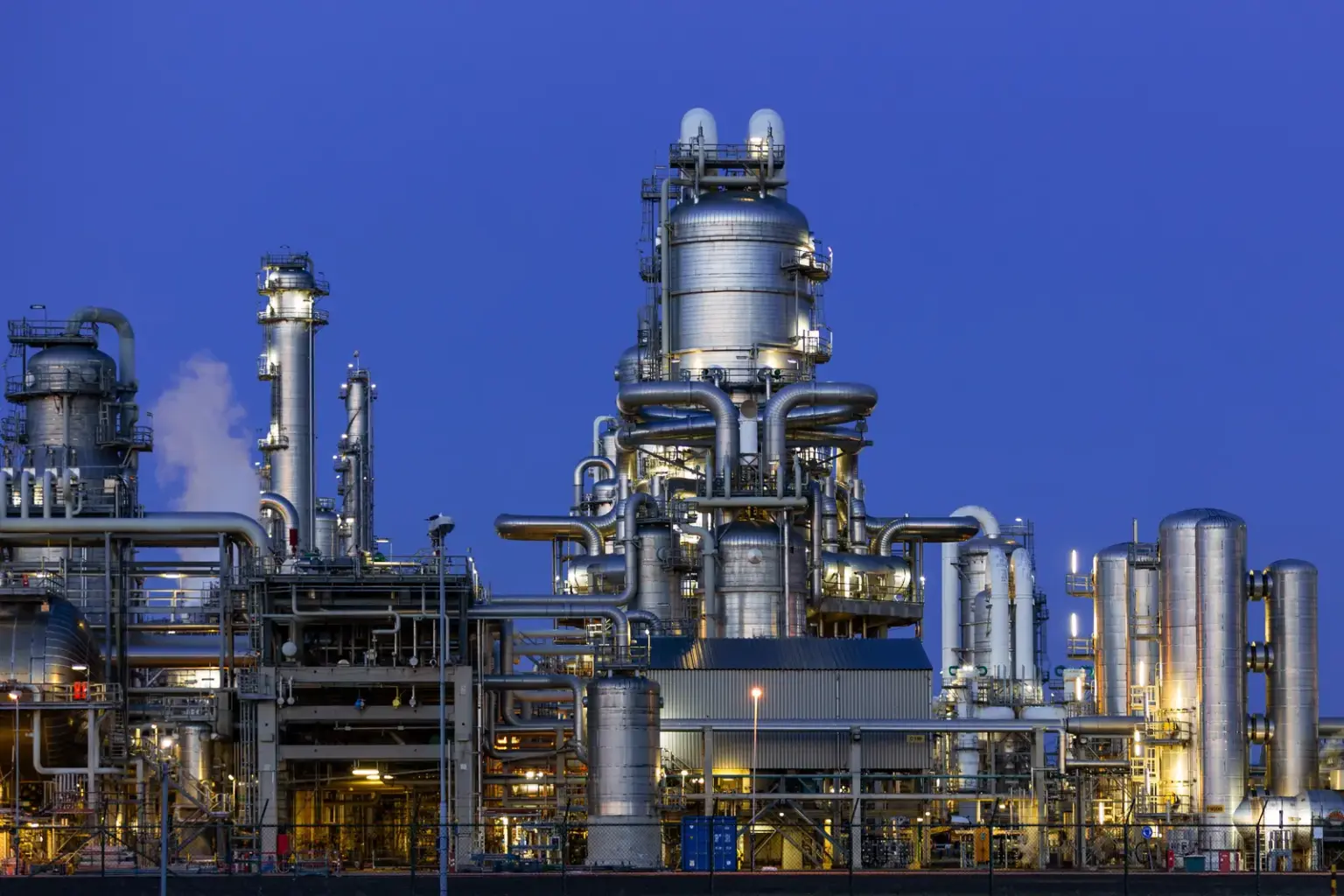 Beleuchtete Industrieanlage mit Rohrleitungen und Prozesstürmen in Rotterdam